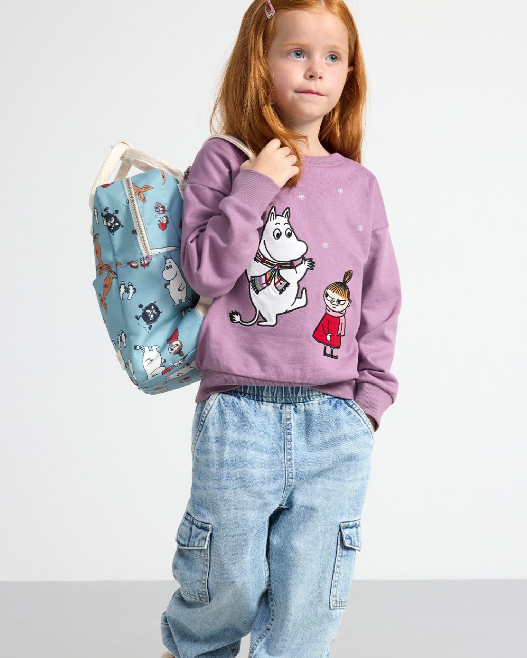 Girl wearing backpack and sweatshirt with Moomintrolls